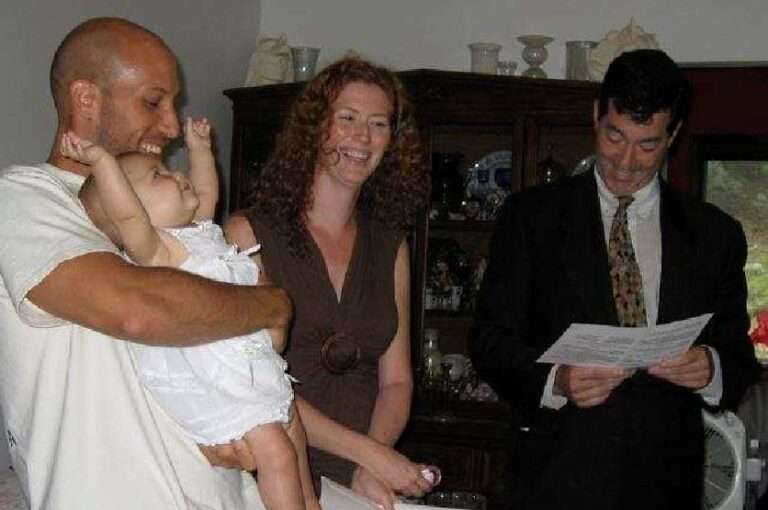 A happy couple holding a baby during a baby naming ceremony with Rabbi Ron Broden.